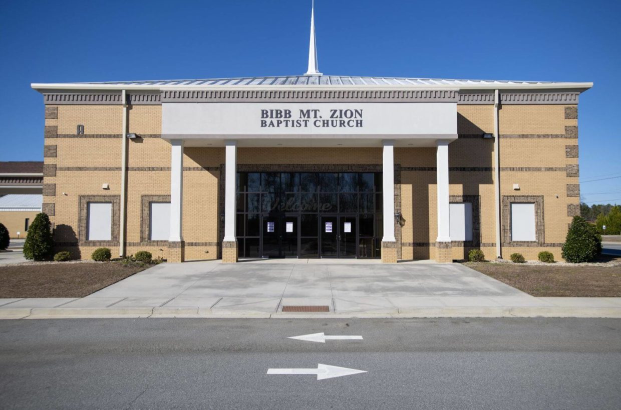 A tall brick church building with covered entry way.