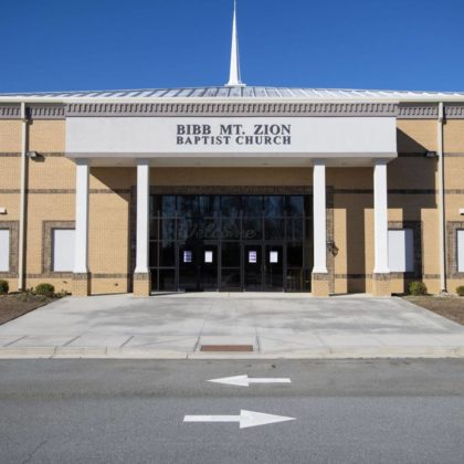 A tall brick church building with covered entry way.