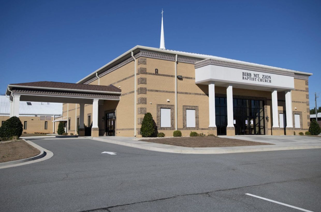 A tall brick church building with covered entry way.