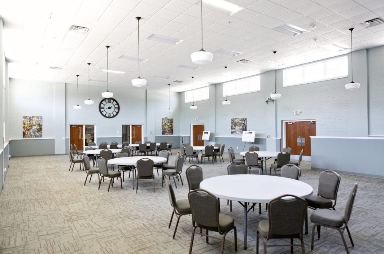A large event room with many large round tables that seat 8.