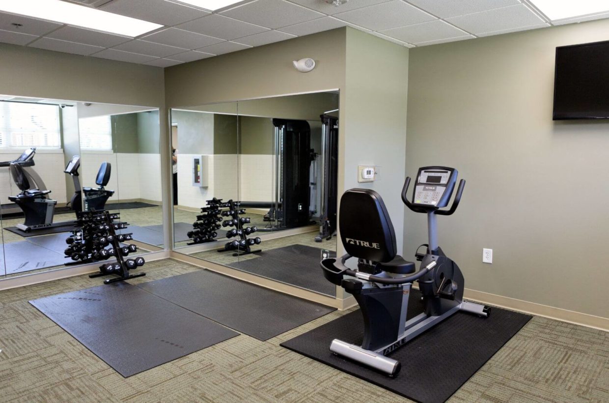 An indoor gym with weights, mirrors, and stationary bike.