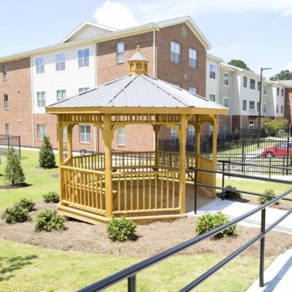 A gazeebo with bench seating outside of an apartment building.