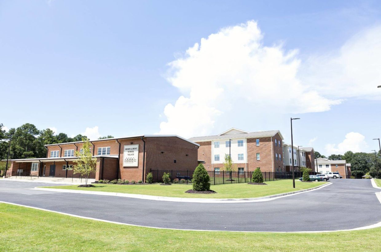 Street view of apartment buildings in the distance after a community building.