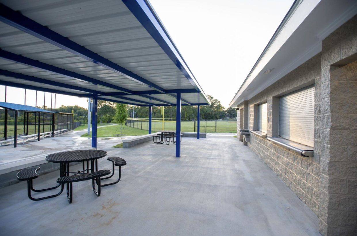 A concrete concession area with tables and roofs over the tables.