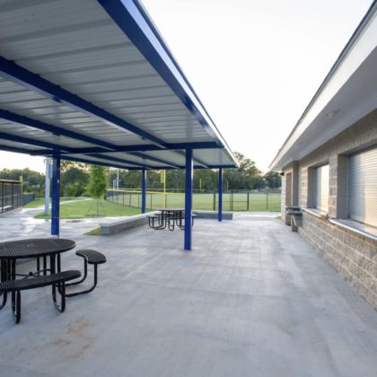 A concrete concession area with tables and roofs over the tables.