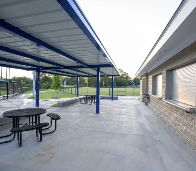 A concrete concession area with tables and roofs over the tables.