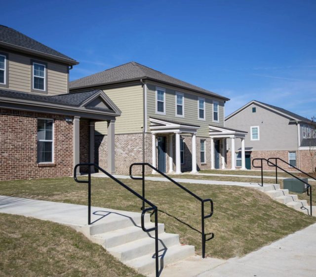 Street view of several duplexes, small nice front yards with stone stairs and walkway leading to the frontdoor.